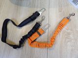 an orange leash and a black lanyard on a wooden floor