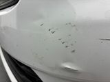 the front of a white car with scratches on the side of it