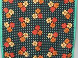 une écharpe à motifs floraux noirs et orange, bordée de vert