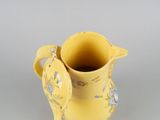 a yellow vase with a bird on it on a table