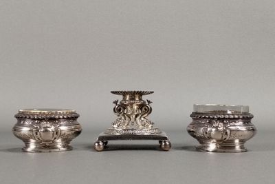 trois vases en argent posés les uns à côté des autres sur une table