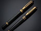 a pair of black and gold fountain pens on a black background