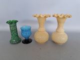 three vases and a glass sitting on a table next to each other
