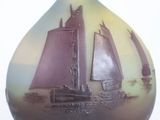 a glass vase with a sailboat on it on a white surface