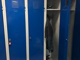 blue lockers in a room with clothes and other items on the floor