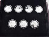 six silver coins in a black case on a table