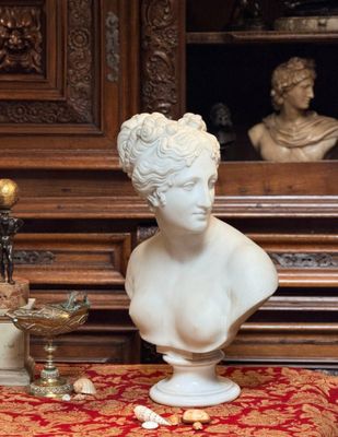 un buste de femme posé sur une table, à côté d'un vase
