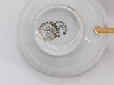 a cup and saucer with a gold handle on a white table