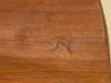 underside of a wooden surfboard with the letter k carved into it
