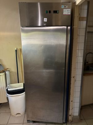a stainless steel refrigerator in a kitchen with a trash can