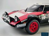 a red and white rally car on display on a white background