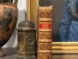 une photo représentant un vase, un livre et une bougie posés sur une étagère