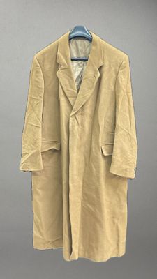 un manteau beige suspendu à un cintre devant un mur gris