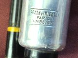 a silver jar with a black handle next to a black pen