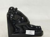 une statue noire représentant un homme assis sur une chaise