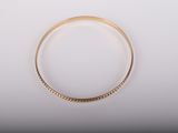 gros plan d'un bracelet en or sur une surface blanche