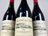 three bottles of red wine sitting on top of a white table
