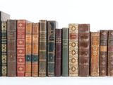 many old books lined up in a row on a white surface