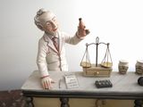 a figurine of a man sitting at a desk with a scale and a cell phone