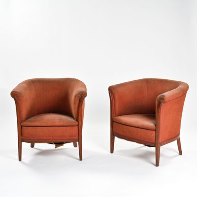 une paire de fauteuils club en cuir orange, avec des pieds et des accoudoirs en bois