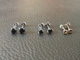 trois paires de boucles d'oreilles à tige posées sur une surface en cuir