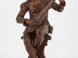 une vieille statue en bronze représentant un homme jouant d'un instrument de musique
