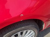 a close up of a red car that is parked on the street