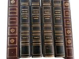 six old books are lined up on a white surface