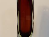 a red glass vase sitting on a black table