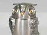 a silver owl figurine sitting on a white surface