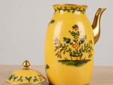 a yellow pitcher with a lid and a flower pot on a table