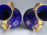 pair of blue vases with gold handles on a white surface