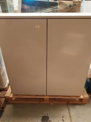 un réfrigérateur blanc posé sur une palette dans un entrepôt