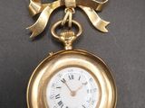 an image of a gold pocket watch with a bow on it