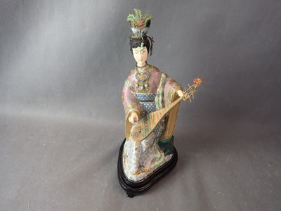 figurine représentant une femme jouant d'un instrument de musique, posée sur un socle noir