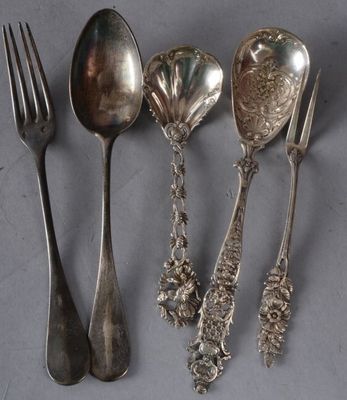 quatre cuillères en argent et une fourchette sont alignées sur une table