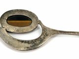 a silver spoon with a tiger ' s eye in it