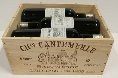 des bouteilles de vin sont disposées dans une caisse en bois posée sur une surface blanche