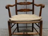 une chaise en bois avec un coussin posé dessus, devant un mur