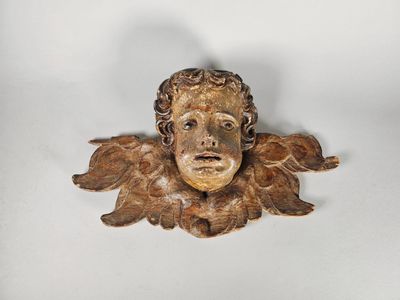 une sculpture en bois représentant un homme ailé sur un fond blanc