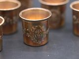 six gold cups with designs on them are lined up on a table