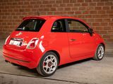 a small red car parked in front of a brick wall