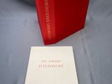un livre ouvert posé sur une table, à côté d'une boîte rouge