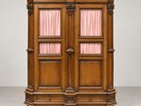 une armoire ancienne en bois surmontée de rideaux roses