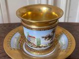 a gold cup and saucer sitting on a wooden table