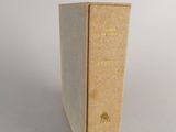 un vieux livre posé sur une table blanche à côté d'un mur blanc