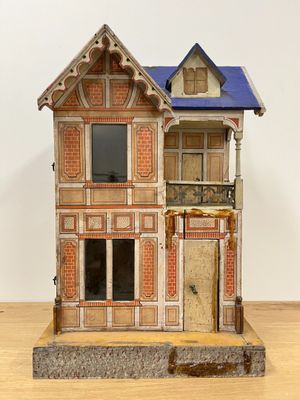 a wooden doll house with a blue roof on a wooden table