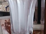 un vase en verre posé sur une table, à côté d'un tableau