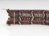 a close up of a silver and pink bracelet on a white surface