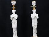 a pair of white and gold candlesticks with statues on them